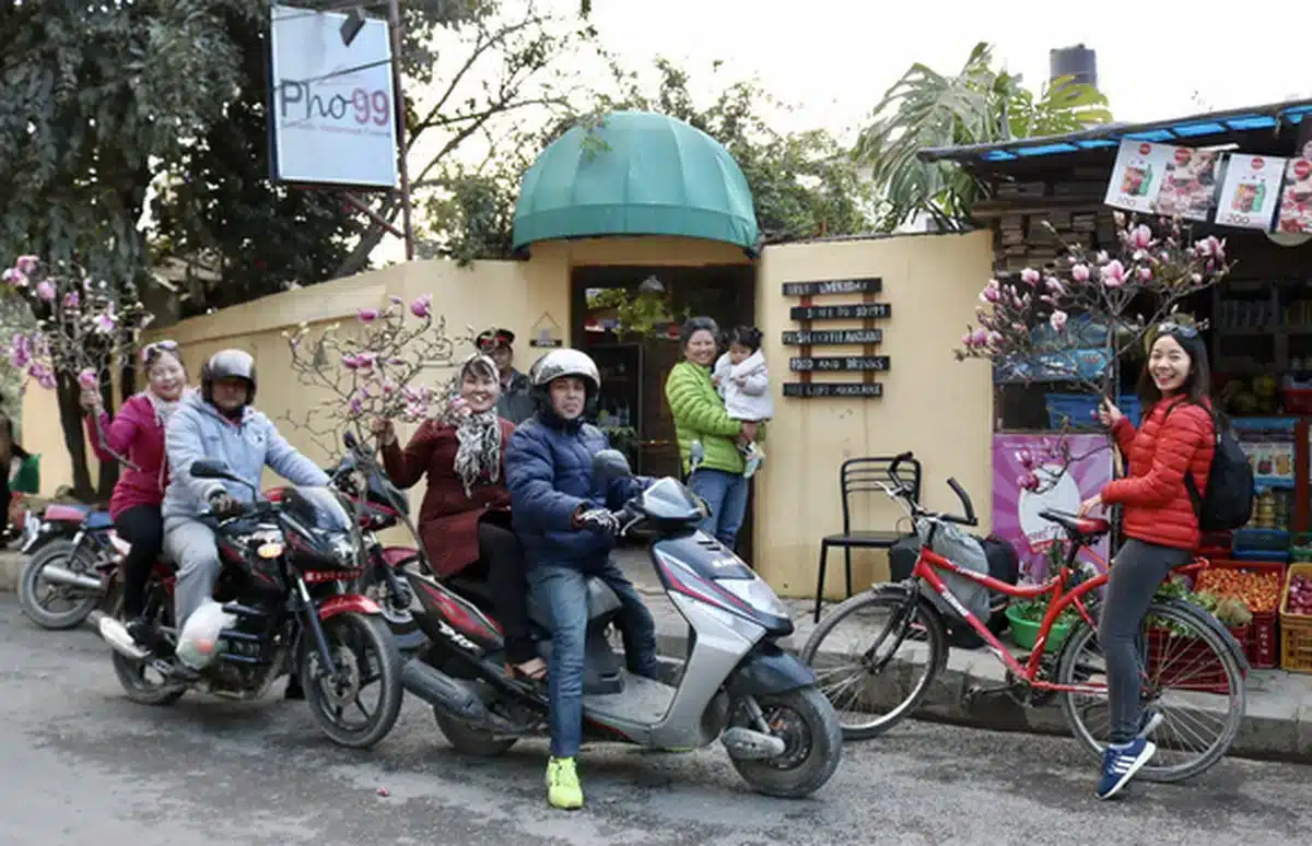 vietnamese riders carrying peach blossom for tet on their motorbikes