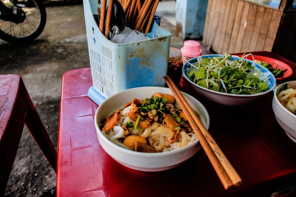 a bowl of mi quang, thick noodles with eggs, meat and herbs