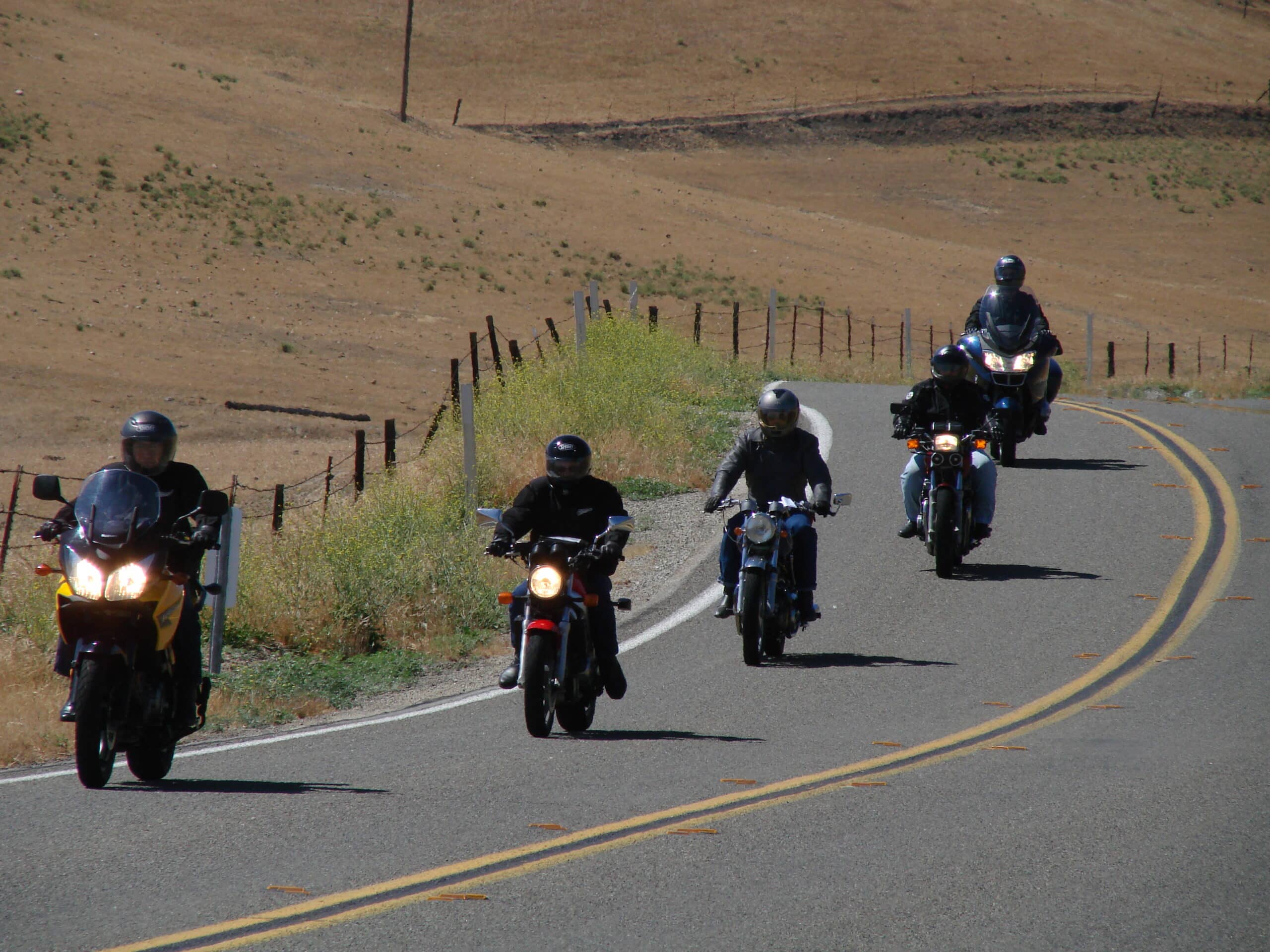 a group of motorcycle riders on tour in a convoy on a tarmac road