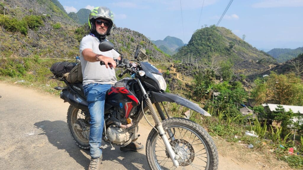 Motorcyclist legally riding a rental bike through the karst mountains of Northern Vietnam.