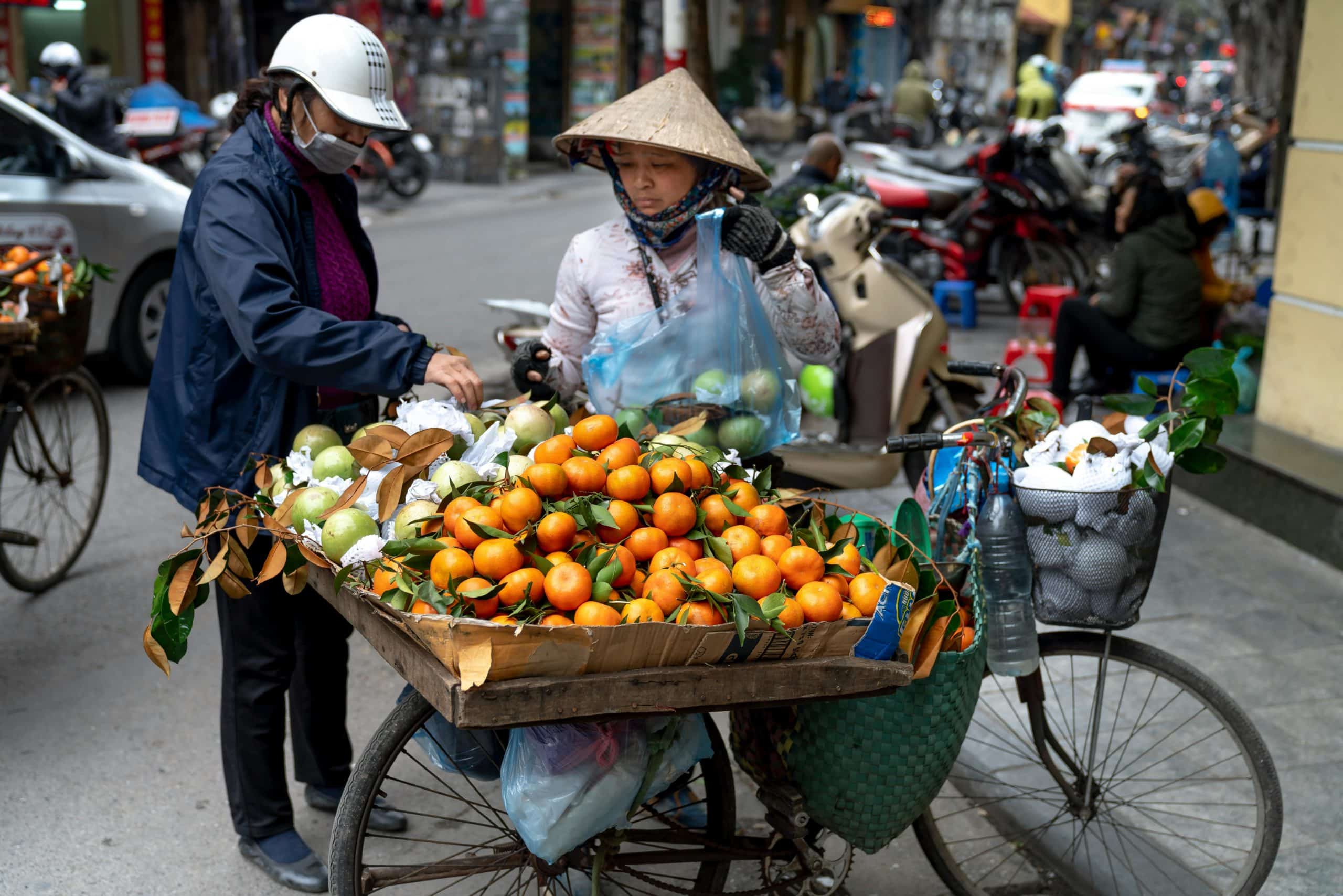 roadside seller sells oranges to local vietnamese woman at tet