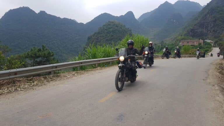 A lead rider on a Royal Enfield Himalayan signaling to the group on a mountain road in Ha Giang.